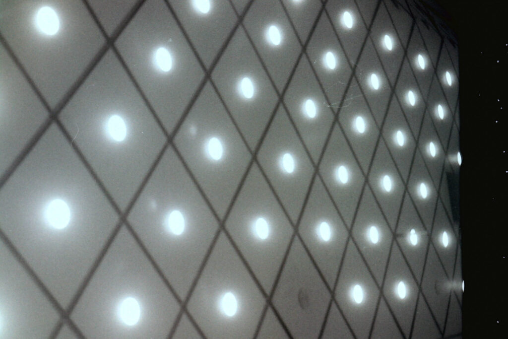 mur de vaisseau spatial éclairé de nombreux spotlights et avec motifs de losange dans la nuit étoilée en noir et blanc