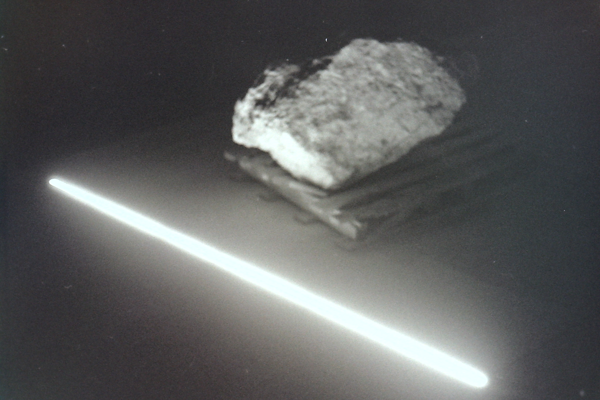 rocher sur palette abîmée posée au sol dans la nuit éclairé par un néon