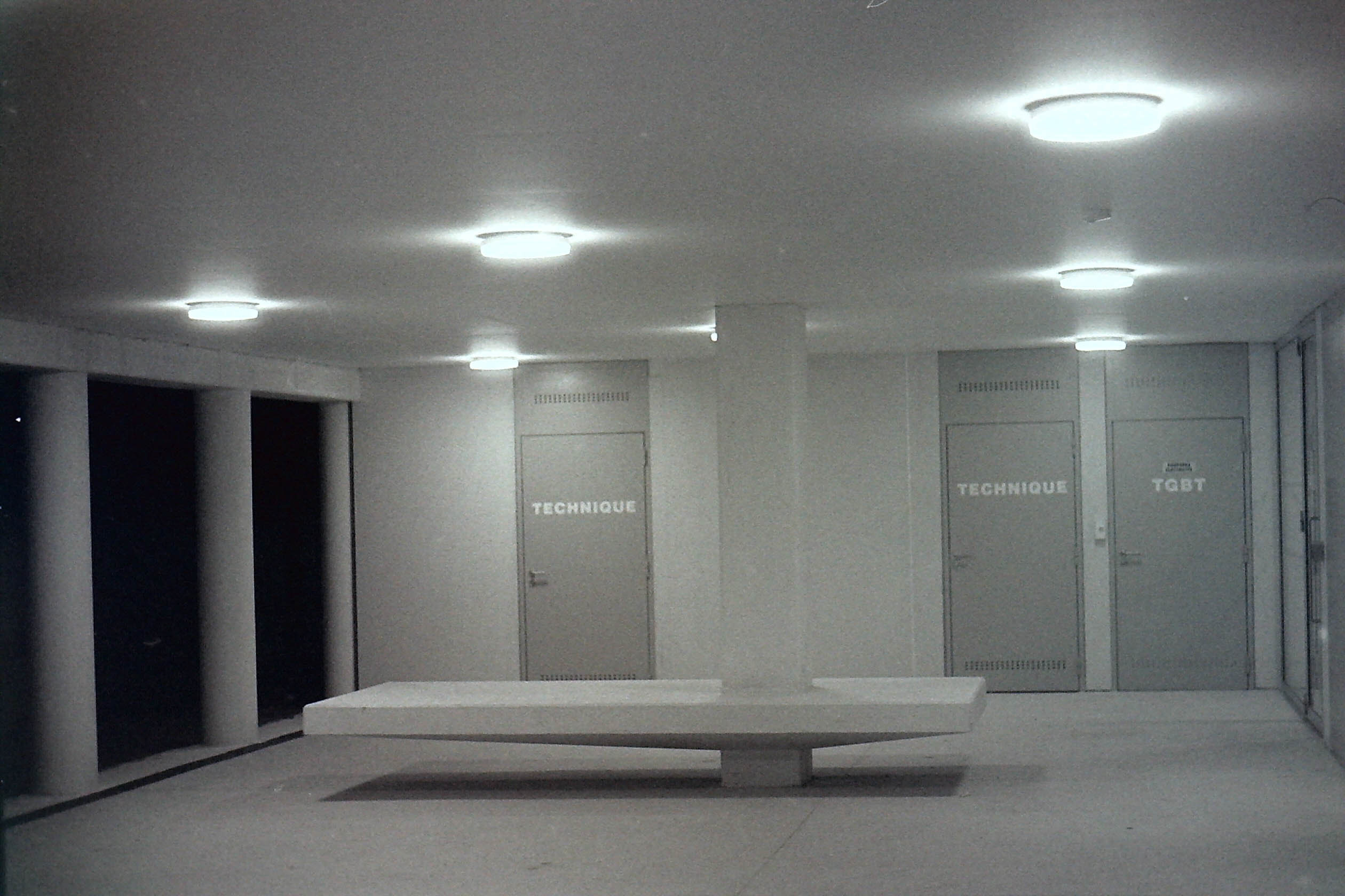 spotlights eclairant un lieu de vie futuriste avec une table et des portes de local technique dans la nuit en noir et blanc