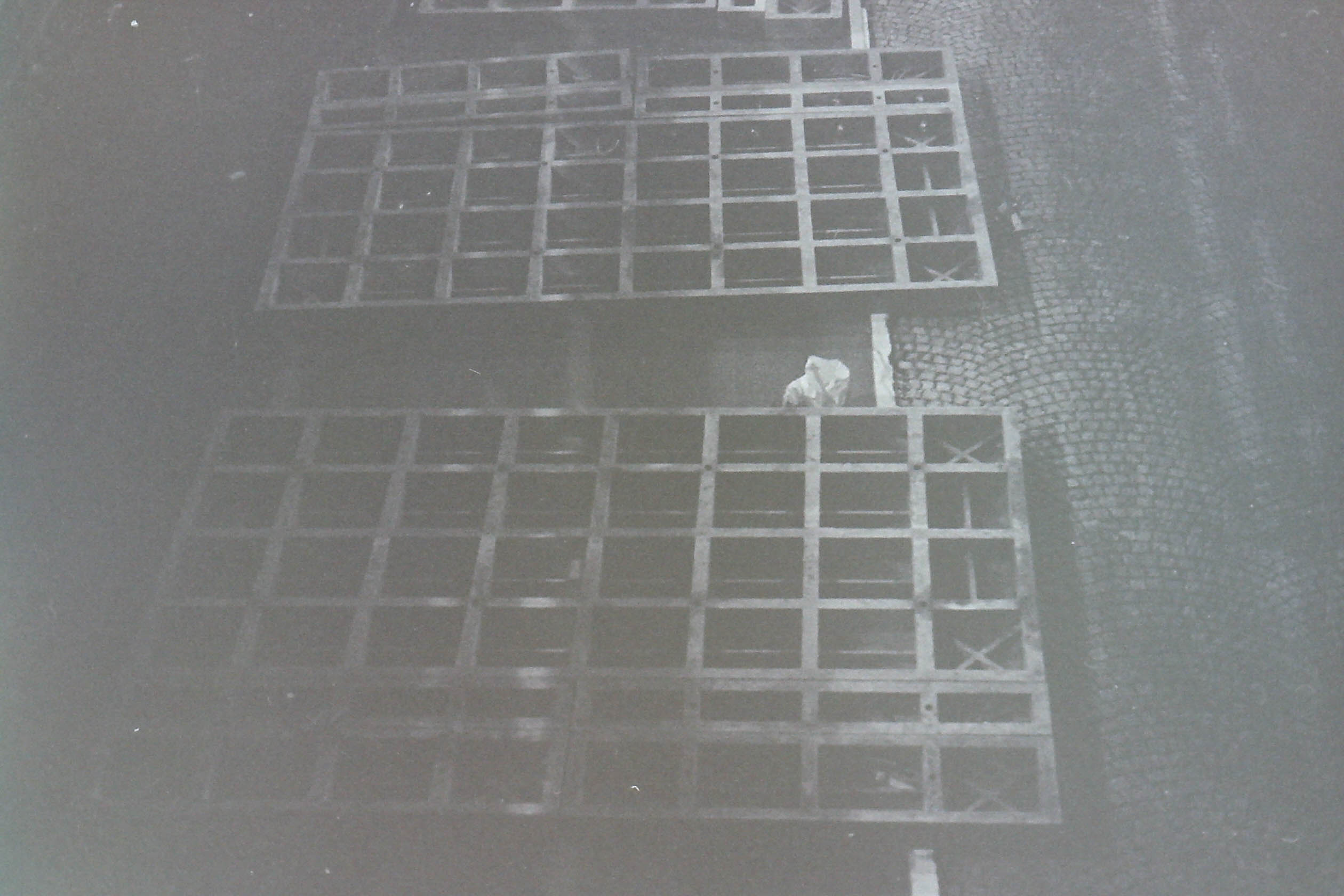 grilles de coffrage de chantier posées sur un sol pavé dans la nuit de paris en noir et blanc